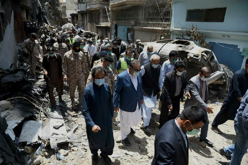 In this photo released Saturday by the Pakistan Civil Aviation Authority, provincial governor Imran Ismail (center in blue coat) and Pakistan’s aviation minister Ghulam Sarwar (center in black waistcoat) visit the site of Friday’s plane crash in Karachi.
(AP/Pakistan Civil Aviation Authority)