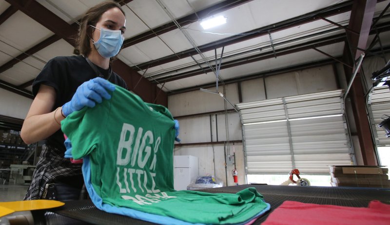 Press operator Hattie Tyler pulls "Big on Little Rock" T-shirts off of a dryer April 3, 2020, at Ink Custom Tees in Maumelle. (Democrat-Gazette file photo/Thomas Metthe)