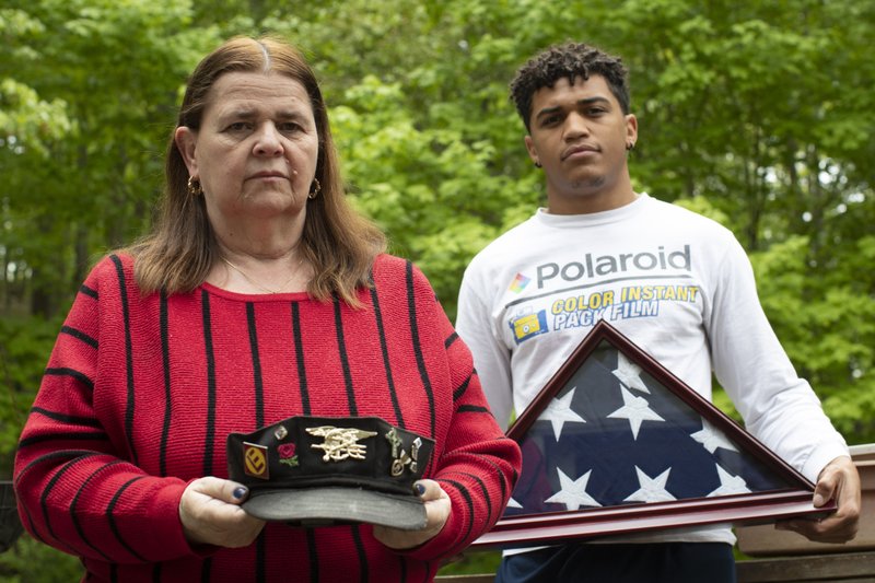 Outside their home in Boonton, N.J., Florence Hopp holds the hat that her husband, Robert Hopp, wore every day, and son J.J. Brania-Hopp holds the American  ag that the military presented after his father’s death. Robert Hopp was among at least 79 residents of a veterans home in Paramus, N.J., to die from the coronavirus. More photos at arkansasonline.com/525tribute/.
(AP/Mary Altaffer)