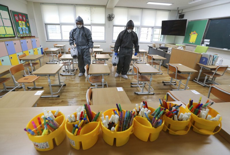 Workers disinfect as a precaution against the new coronavirus ahead of school reopening in a class at an elementary school in Gwangju, South Korea, Tuesday, May 26, 2020.