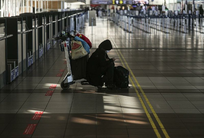 A passenger sits near the empty check-in counter for Latam airlines Tuesday at the Arturo Merino Benitez airport in Santiago, Chile. South America’s biggest carrier is seeking U.S. bankruptcy pro- tection as it grapples with a sharp downturn in air travel sparked by the pandemic. More photos at arkansasonline.com/527latam/ 
(AP/Esteban Felix) 
