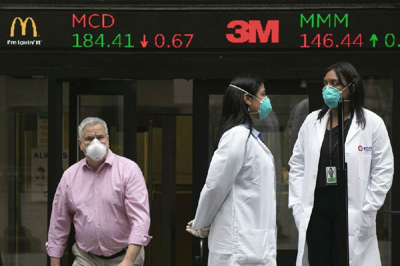 Health care workers prepare to distribute masks Tuesday to people arriving at the New York Stock Exchange where the trading floor partially reopened. It had been closed since mid-March because of the coronavirus. (AP/Mark Lennihan) 

