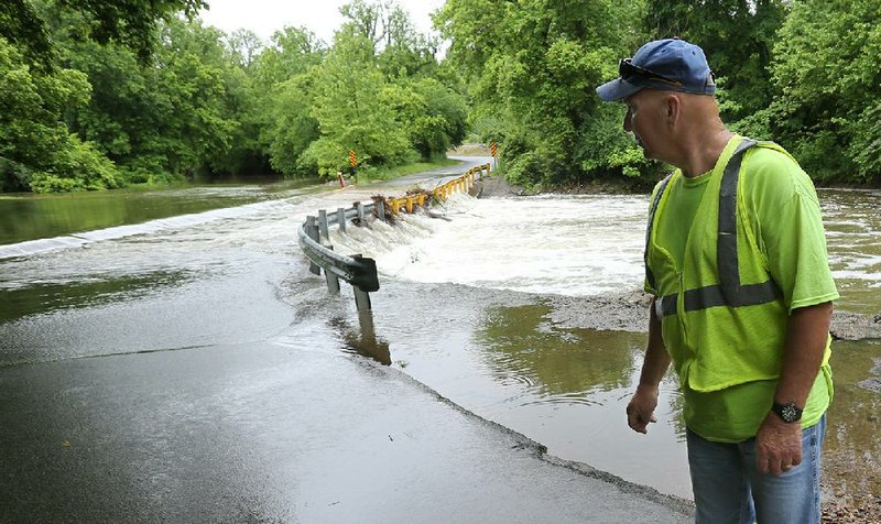 Terry Franks, with the city of Johnson Public Works, monitors the level of water and debris from Clear Creek Tuesday, May 26, 2020, running over the low water bridge on Ball Street. Heavy rains in Northwest Arkansas caused the closure. When the water recedes and the debris is removed the street will be reopened. Check out nwaonline.com/200527Daily/ and nwadg.com/photos for a photo gallery.
(NWA Democrat-Gazette/David Gottschalk)
