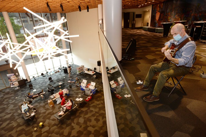 Musician Ben Harris performs Wednesday for donors in a Red Cross blood drive hosted by the Walton Arts Center in Fayetteville. With no shows in the center planned until fall because of the coronavirus pandemic, the center wanted to give back to the community by hosting the drive complete with live music and providing paid work for Harris and local band, Smokey and the Mirror. (NWA Democrat-Gazette/Andy Shupe)