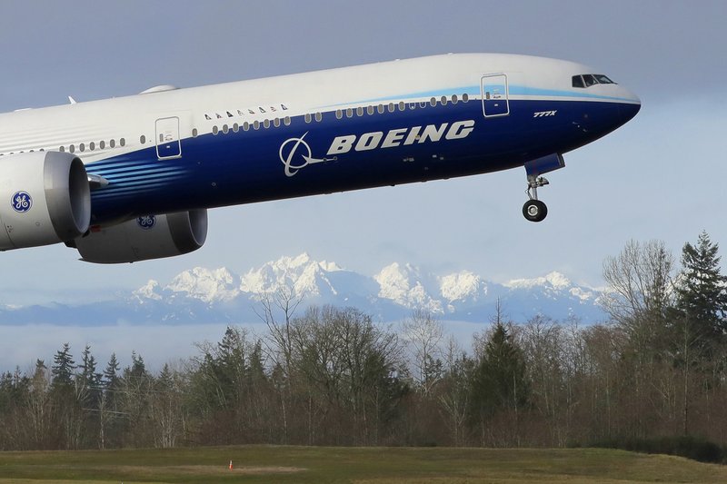 FILE - In this Jan. 25, 2020, file photo a Boeing 777X airplane takes off on its first flight with the Olympic Mountains in the background at Paine Field in Everett, Wash. Boeing on Wednesday, May 27, is cutting more than 12,000 jobs through layoffs and buyouts as the coronavirus pandemic seizes the travel industry. And the aircraft maker says more cuts are coming. (AP Photo/Ted S. Warren, File).