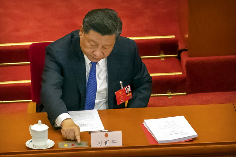 Chinese President Xi Jinping reaches to vote on a piece of national security legislation concerning Hong Kong during the closing session of China's National People's Congress (NPC) in Beijing, Thursday, May 28, 2020. China's ceremonial legislature has endorsed a national security law for Hong Kong that has strained relations with the United States and Britain. (AP Photo/Mark Schiefelbein)