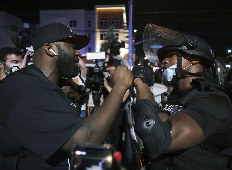 A Memphis Police Department officer fist-bumps a protester in an attempt to bring the protest over the death of George Floyd to a peaceful conclusion early Thursday, May 28, 2020, in Memphis.