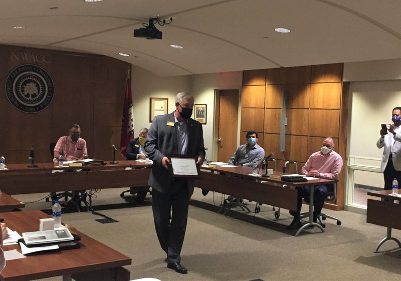 Jim Hall, executive director of community and government relations, receives a plaque at the Northwest Arkansas Community College board meeting Wednesday in recognition of his 29 years working for the college. Hall is retiring this summer. (NWA Democrat-Gazette/Dave Perozek)