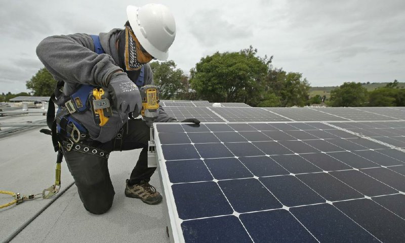A worker installs solar panels on the roof of a building in Hayward, Calif., in April. Arkansas regulators have asked to intervene in  a federal petition that could alter how consumers and businesses are compensated for solar power generated at homes and businesses.
(AP/Ben Margot)