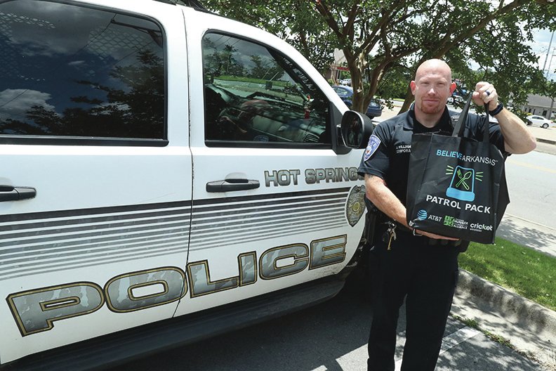 Hot Springs Police Cpl. Joey Williams, the department's public information officer, displays one of the 108 "patrol packs" every officer in the department received Wednesday to carry in their units. The packs contain a variety of nonperishable foods that can be given out to those in need the officer comes across in the city. (The Sentinel-Record/Richard Rasmussen)