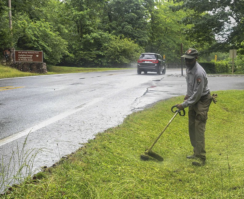 National Park Service employee Derrick Pickens trims the grass at Gulpha Gorge Campground on Thursday, in preparation for the area reopening. - Photo by Grace Brown of The Sentinel-Record