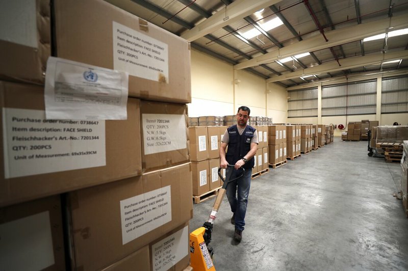 A worker pulls a cart of coronavirus aid items being prepared for shipment at a World Health Organization facility, part of the International Humanitarian City in Dubai, United Arab Emirates, in this Thursday, March 5, 2020, file photo.