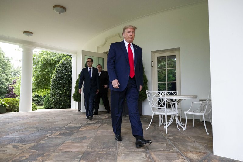 President Donald Trump walks out of the Oval Office of the White House, followed by Treasury Secretary Steven Mnuchin and others, to speak in the Rose Garden on Friday, May 29, 2020, in Washington.
