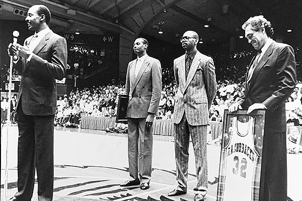 Sidney Moncrief (front) speaks to the Barnhill Arena crowd while Marvin Delph (left), Ron Brewer (center) and Eddie Sutton listen behind him on March 3, 1990, in Fayetteville. 