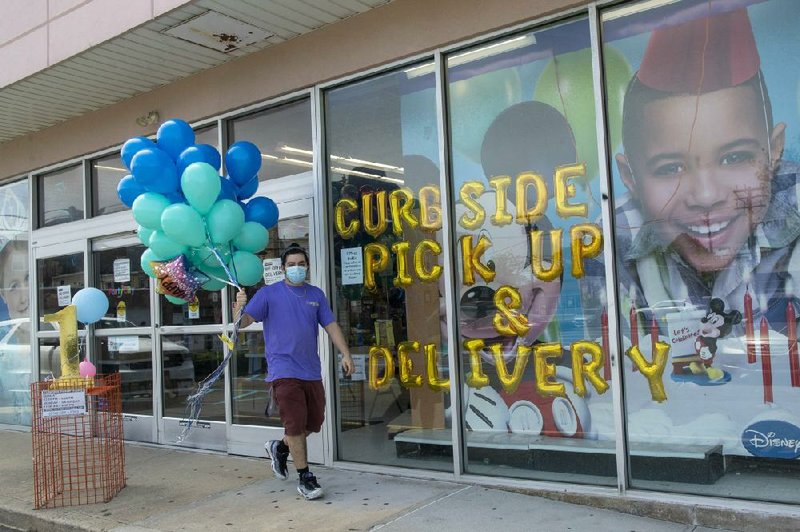 A Party City employee delivers balloons to a customer curbside Wednesday in Oceanside, N.Y. About 41 million people have applied for U.S. unemployment benefits since the coronavirus outbreak.
(AP/Mary Altaffer)