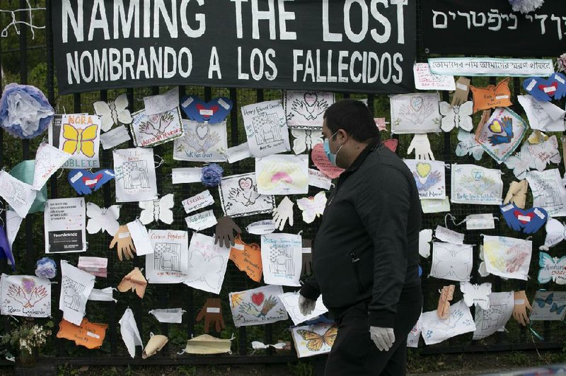 A man stops Thursday to look at tributes for covid-19 victims left on a fence outside Brooklyn’s Green-Wood Cemetery in New York. The memorial is part of the Naming the Lost project, which seeks to humanize the victims who are often listed as statistics. The wall features banners that read “Naming the Lost” in six languages — English, Spanish, Mandarin, Arabic, Hebrew and Bengali. More photos at arkansasonline.com/529covid/
(AP/Mark Lennihan)