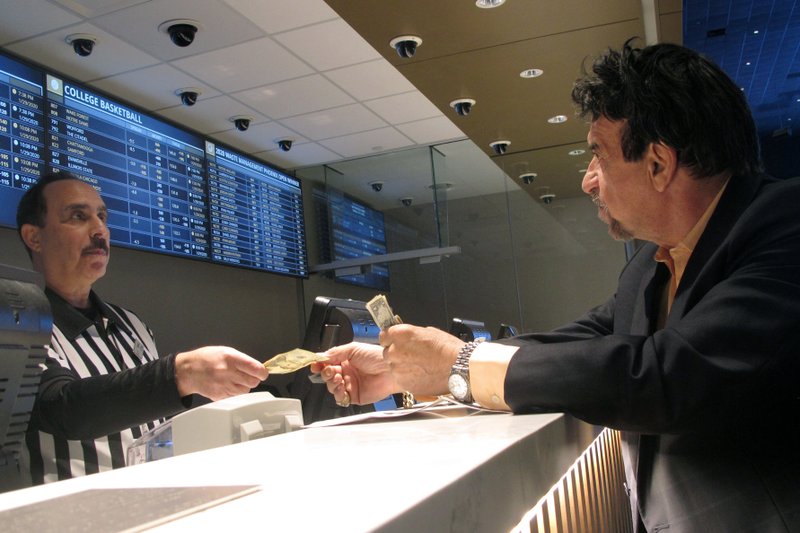  In this Jan. 29, 2020, file photo, a gambler makes bets on the upcoming Super Bowl at Bally's casino in Atlantic City N.J. The coronavirus pandemic could lead to a quicker expansion of sports betting and internet gambling in the U.S. as states deal with huge budget deficits and look for new tax revenue wherever they can find it.(AP Photo/Wayne Parry, File)