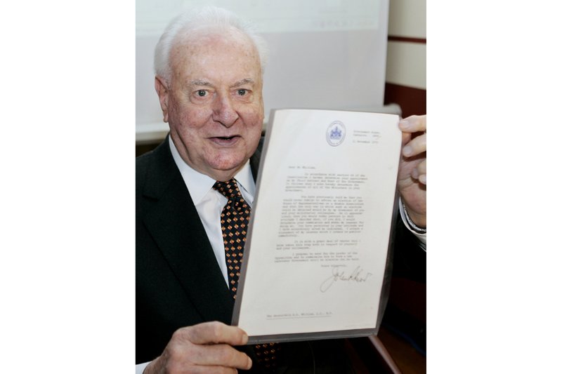 FILE - In this Nov. 7, 2005, file photo, former Australian Prime Minister Gough Whitlam holds up the original copy of his dismissal letter he received from then Governor-General Sir John Kerr on Nov. 11, 1975, at a book launch in Sydney, Australia. The High Court's majority decision in historian Jenny Hocking's appeal on Friday, May 29, 2020 overturned lower court rulings that more than 200 letters between the monarch of Britain and Australia and Governor-General Sir John Kerr before he dismissed Prime Minister Gough Whitlam's government were personal and might never be made public. (AP Photo/Mark Baker, File)