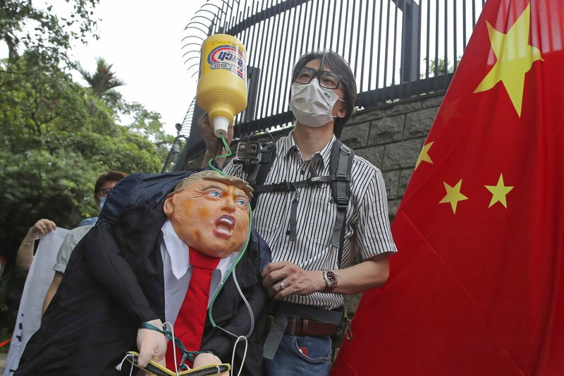 Pro-China supporters hold the effigy of U.S. President Donald Trump and Chinese national flag outside the U.S. Consulate during a protest in Hong Kong, Saturday, May 30, 2020. President Donald Trump has announced a series of measures aimed at China as a rift between the two countries grows. He said Friday that he would withdraw funding from the World Health Organization, end Hong Kong's special trade status and suspend visas of Chinese graduate students suspected of conducting research on behalf of their government. (AP Photo/Kin Cheung)