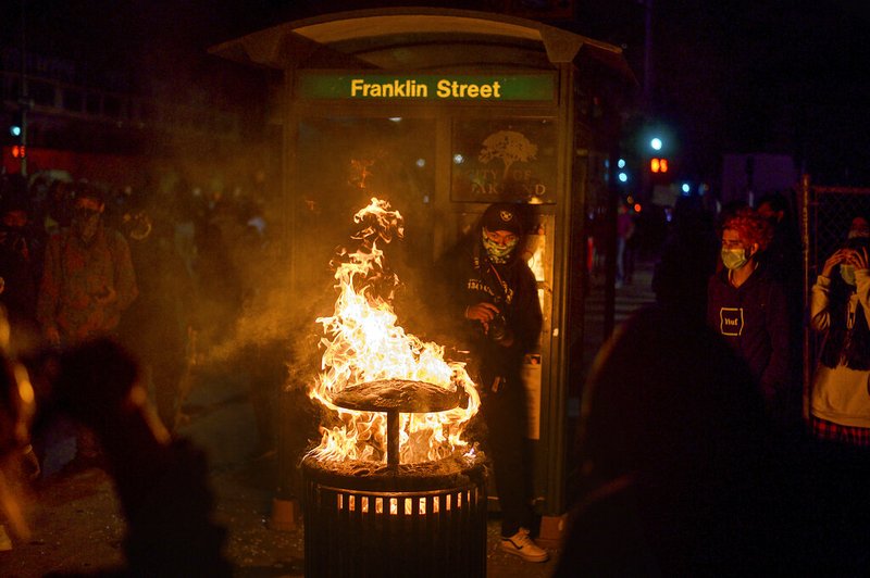 A fire burns in a trash can as demonstrators protest in Oakland, Calif. on Friday, May 29, 2020, against the Monday death of George Floyd in police custody in Minneapolis.