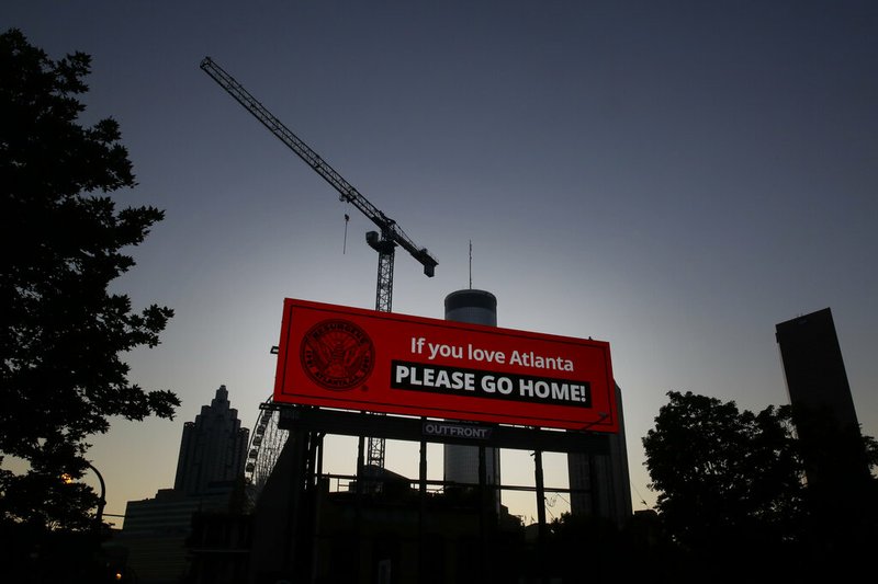 A sign in downtown Atlanta reads "If you love Atlanta PLEASE GO HOME" as the sun rises Saturday morning, May 30, 2020, in the aftermath of a demonstration spurred by the death of George Floyd in Minneapolis.