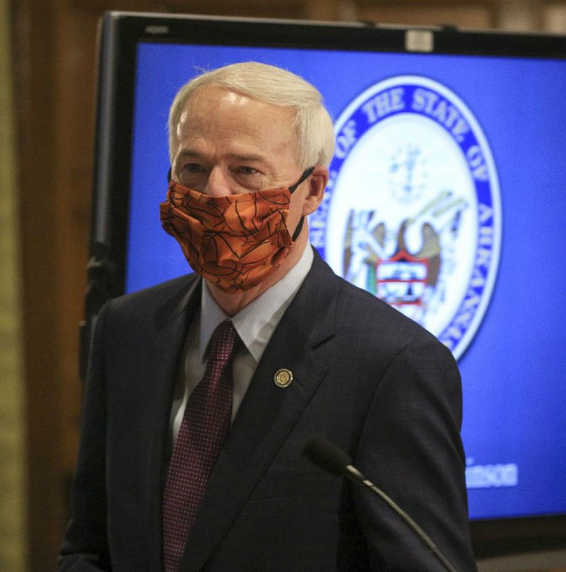 Gov. Asa Hutchinson arrives wearing a mask Friday May 29 for the daily COVID-19 briefing at the state Capitol.