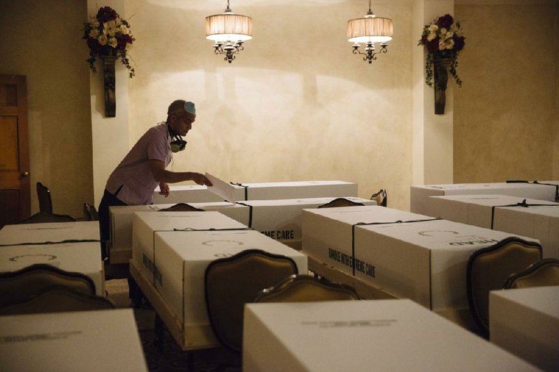 Standing among cremation boxes, a mortuary director completes paperwork earlier this year at a funeral home in the Queens borough of New York City.
(Bloomberg News/Angus Mortant)