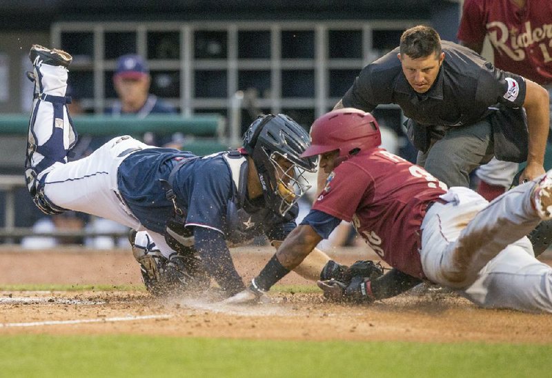 Home plate umpire Justin Robinson watches as Northwest Arkansas Naturals catcher Luis Villegas tries to tag out Yanio Perez of the Frisco RoughRiders in a 2018 game at Arvest Ballpark in Springdale. Minor-league umpires have dreams of moving up to Major League Baseball, but some realize the coronavirus pandemic might end their careers.
(NWA Democrat-Gazette/Ben Goff)