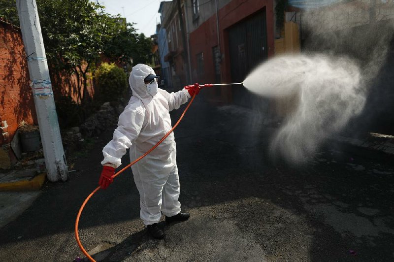 A public-safety worker sprays disinfectant Friday in the streets of the El Rosario neighborhood of Mexico City after a recent cluster of coronavirus cases were reported there.
(AP/Rebecca Blackwell)