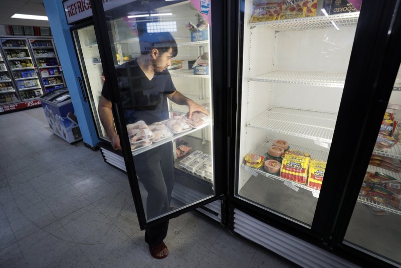 Hardik Kalra stocks meat in a cooler at a local super market, Friday, May 29, 2020, in Des Moines, Iowa. As if trips to the grocery store weren't nerve-racking enough, shoppers lately have seen the costs of meat, eggs and even potatoes soar as the coronavirus has disrupted processing plants and distribution networks. (AP Photo/Charlie Neibergall)