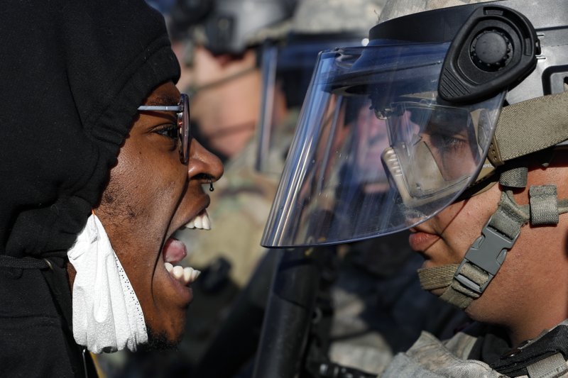 Protesters and National Guardsmen face off on East Lake Street, Friday, May 29, 2020, in St. Paul, Minn. The massive protests sweeping across U.S. cities following the police killing of a black man in Minnesota have elevated fears of a new surge in cases of the coronavirus. Images showing thousands of screaming, unmasked protesters have sent shudders through the health community, who worry their calls for social distancing during the demonstrations are unlikely to be heard.  (AP Photo/John Minchillo)