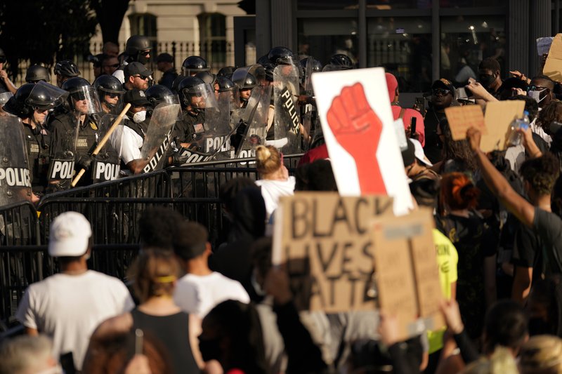 Demonstrators stand in front of police in riot gear as they gather to protest the death of George Floyd, Saturday, May 30, 2020, near the White House in Washington. Floyd died after being restrained by Minneapolis police officers. (AP Photo/Evan Vucci)