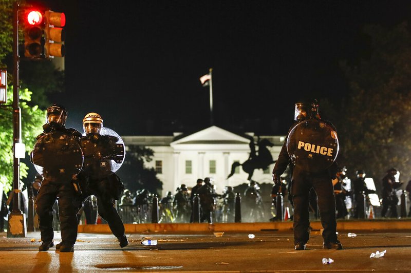 Police stand on H Street near the White House in Washington as demonstrators protest the death of George Floyd on Sunday, May 31, 2020.