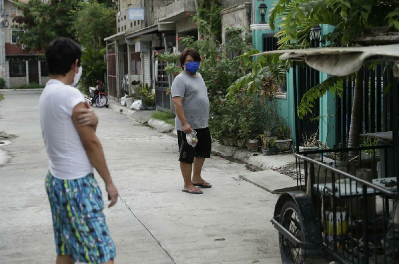 Christopher Bagay (left), a cruise ship worker, talks to his neighbor last week after returning to his home in Laguna province in the Philippines. Bagay said quarantines in Europe and Manila kept him away for months.
(AP/Aaron Favila)