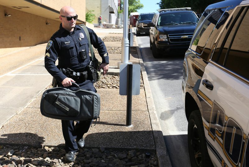 Cpl. Matthew Townsend loads his gear Friday into his patrol vehicle parked on south Block Avenue on the east side of the police station in Fayetteville. The City Council asked for revisions to a conceptual site plan for a new police headquarters to be built at Porter Road and Deane Street, which will include a new main station, indoor firing range and buildings for storage and garages. Go to nwaonline.com/200601Daily/ and nwadg.com/photos for a photo gallery. (NWA Democrat-Gazette/David Gottschalk)