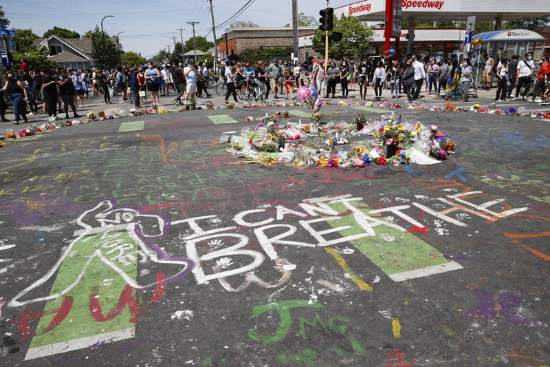 Mourners gather to place flowers at a makeshift memorial for George Floyd at the corner of Chicago Avenue and East 38th Street on Sunday in Minneapolis. Protests continued following the death of Floyd, who died after being restrained by Minneapolis police officers on May 25. - AP Photo/John Minchillo