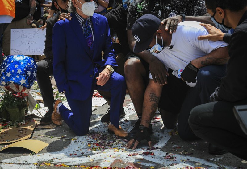 An emotional Terrence Floyd, second from right, is comforted as he touch the spot at the intersection of 38th Street and Chicago Avenue, Minneapolis, Minn., where his brother George Floyd, encountered police and died while in their custody, Monday, June 1, 2020. (AP Photo/Bebeto Matthews)

