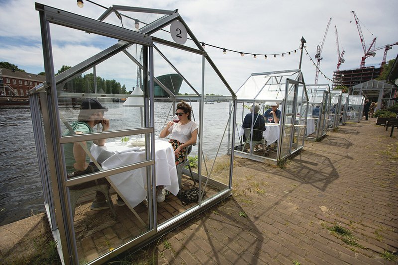 The Associated Press RELAXING LOCKDOWN: Customers seated in small glasshouses enjoy lunch at the Mediamatic restaurant in Amsterdam, Netherlands, Monday. The government took a major step to relax the coronavirus lockdown, with bars, restaurants, cinemas and museums reopening under strict conditions, abiding by government guidelines and respecting social distancing to help curb the spread of the COVID-19 coronavirus.