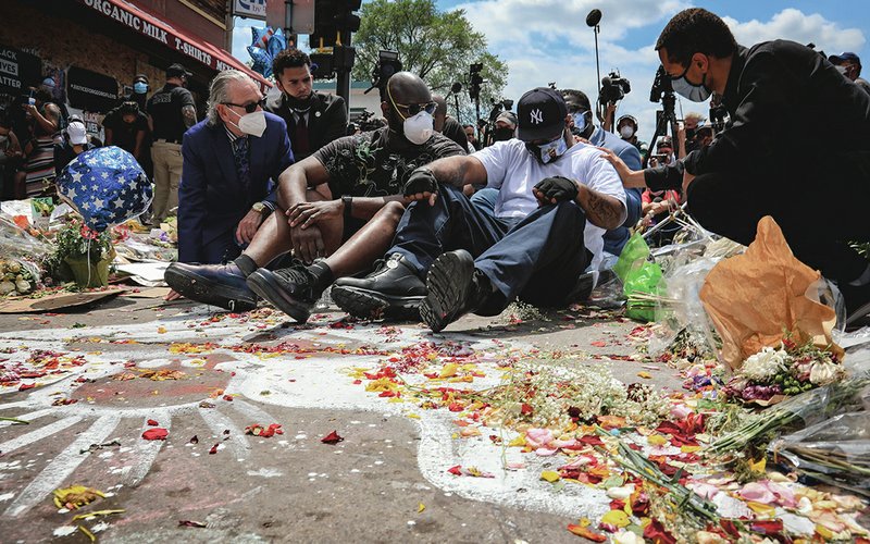 The Associated Press EMOTIONAL BROTHER: An emotional Terrence Floyd, second from right, is comforted as he sits at the spot at the intersection of 38th Street and Chicago Avenue, Minneapolis, Minn., where his brother George Floyd, encountered police and died while in their custody, Monday.