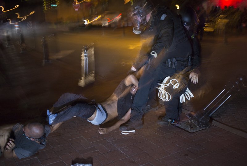 Officers arrest protesters Monday during a rally at the Bentonville square. Check out nwaonline.com/200602Daily/ for today’s photo gallery. (NWA Democrat-Gazette/Charlie Kaijo)