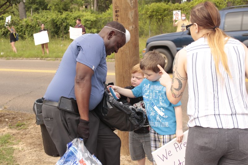 Kelly Owens offers refreshments to Michael Camel and Samuel Johnson during a demonstration against police brutality at Old City Park on Monday, June 1. The children's mother Gabrielle Burger is also pictured. 