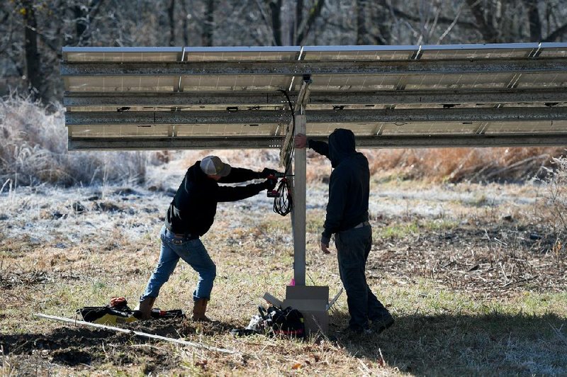 Employees of Seal Solar install an inverter box on a solar array in December at a home in Fayetteville. (NWA Democrat-Gazette/J.T. Wampler) 
