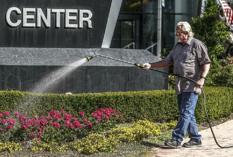 Bill Thompson waters a bed of flowers Monday in front of the convention center in Owensboro, Ky. (AP/The Messenger-Inquirer/Greg Eans) 
