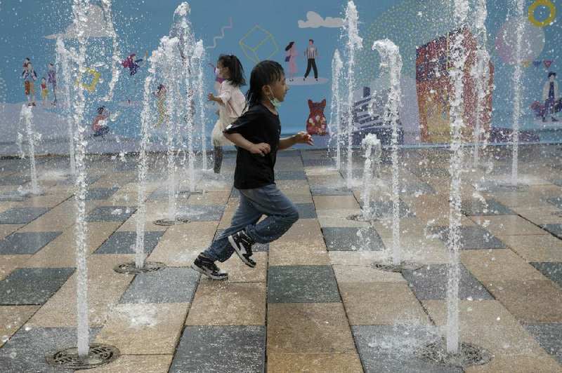 Children play in the middle of the water fountains Monday in Beijing. (AP/Ng Han Guan) 
