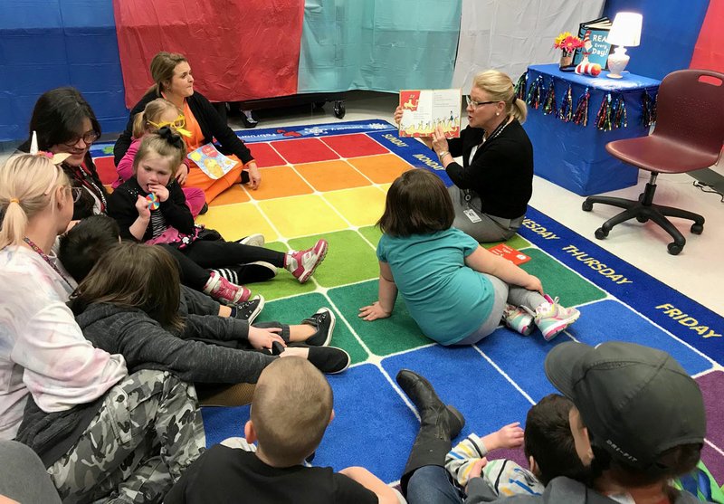 Photo submitted Grace Davis, right, reads to a group of students at Allen Elementary School last fall. Davis, who serves as director of teacher quality and community relations for the Siloam Springs School District, is retiring after 28 years in education.