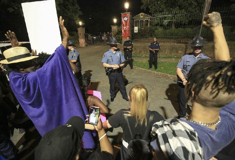 Protesters gather Tuesday night outside the Governor’s Mansion as State Police officers stand guard. The group had marched there from a demonstration at the state Capitol. (Arkansas Democrat-Gazette/Staton Breidenthal) 