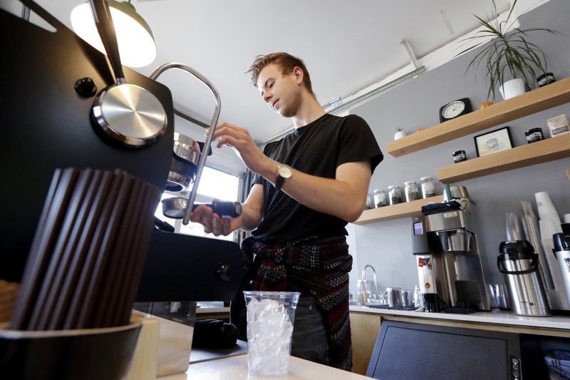 In this Nov. 4, 2019 file photo, barista Porter Hahn makes an iced coffee drink for a customer in a coffee shop in Seattle. U.S. services companies grew at a faster pace in February 2020 than the previous month, an indication that the economy is still expanding, despite growing concerns about global coronavirus outbreak.  The Institute for Supply Management said Wednesday, March 4, 2020 that its service-sector index rose to 57.3 from 55.5 in January.  (AP Photo/Elaine Thompson, File)