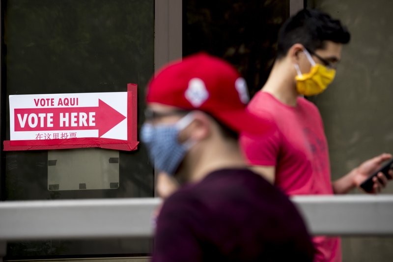 People wear masks as they wait in line to vote at a voting center during primary voting in Washington, Tuesday, June 2, 2020. (AP Photo/Andrew Harnik)