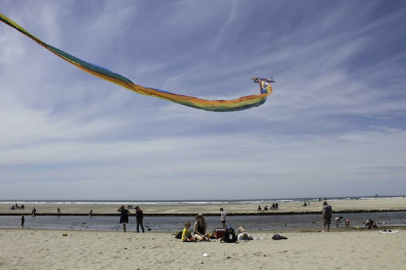 Gwen Partlow and her sons, Cameron, 5, and Casey, 2, fly a kite late last month at the beach in Cannon Beach, Ore. Thousands of small, tourist-dependent towns nationwide are struggling to balance coronavirus fears with economic survival. More photos at arkansasonline.com/64beach/.
(AP/Gillian Flaccus)
