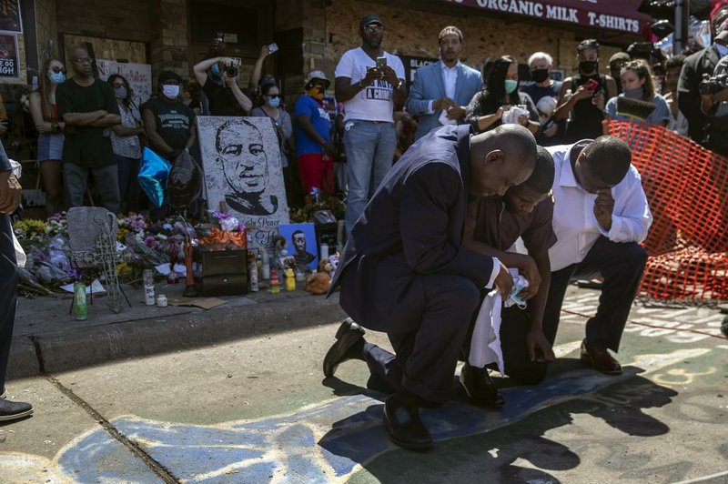 Quincy Mason Floyd (center), son of George Floyd, and attorney Benjamin Crump (left) kneel Wednesday at the site where Floyd’s father died in Minneapolis. More photos at arkansasonline.com/64protests/.
(The New York Times/Victor J. Blue)